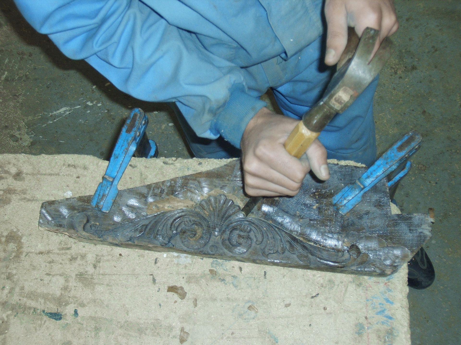 Una persona está trabajando en un trozo de metal con un martillo.