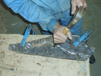 Una persona está trabajando en un trozo de metal con un martillo.