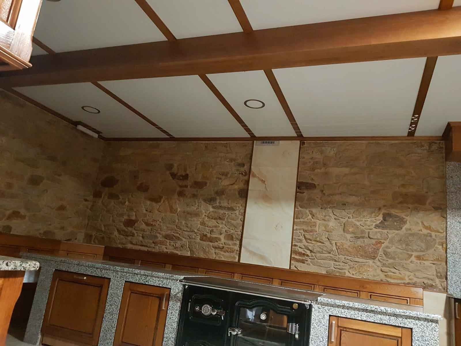 Una cocina con pared de piedra y vigas de madera.