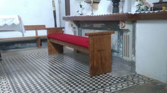 Un banco de madera con un cojín rojo en una iglesia.