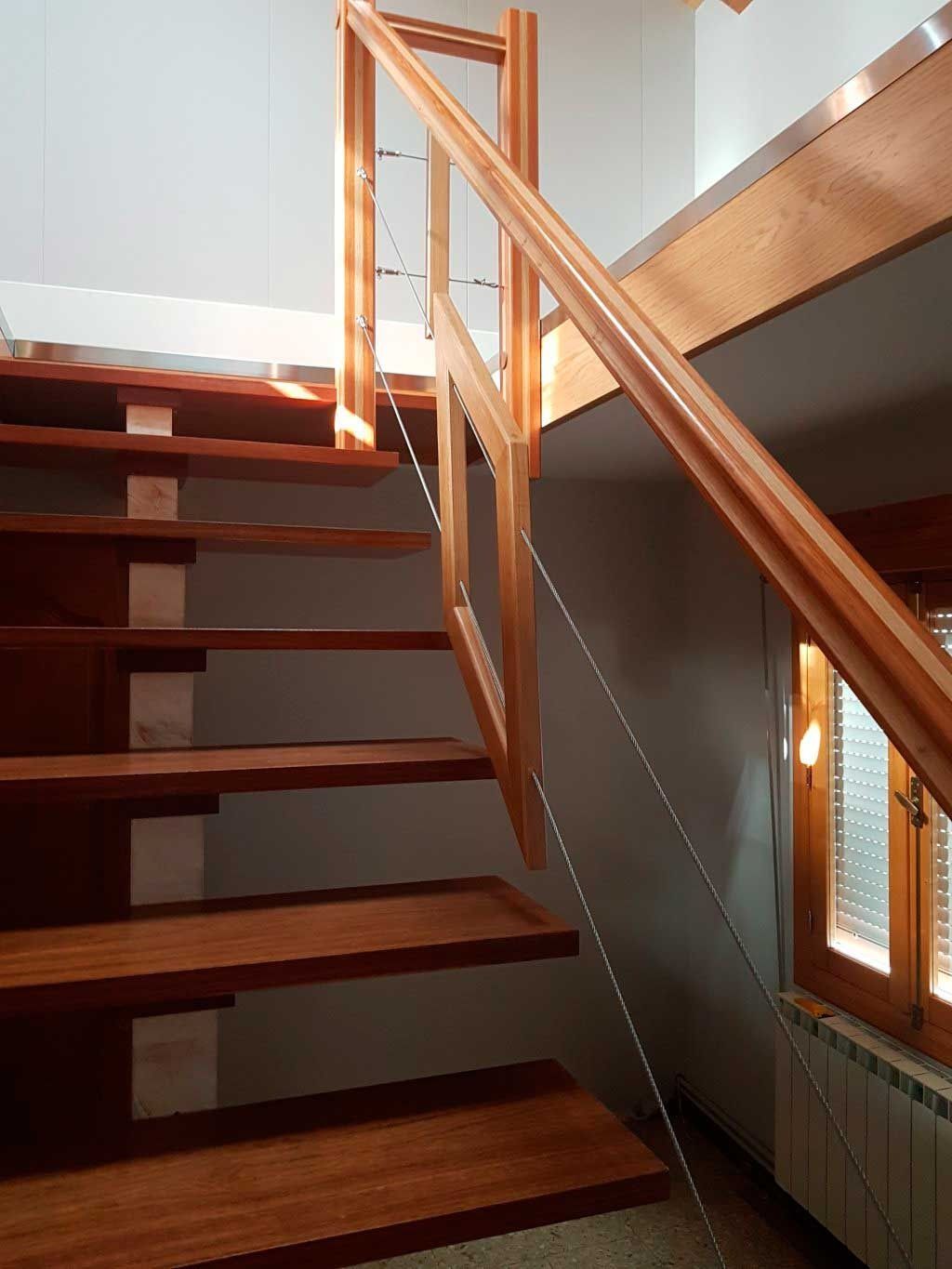 Una escalera de madera en una habitación con ventana.