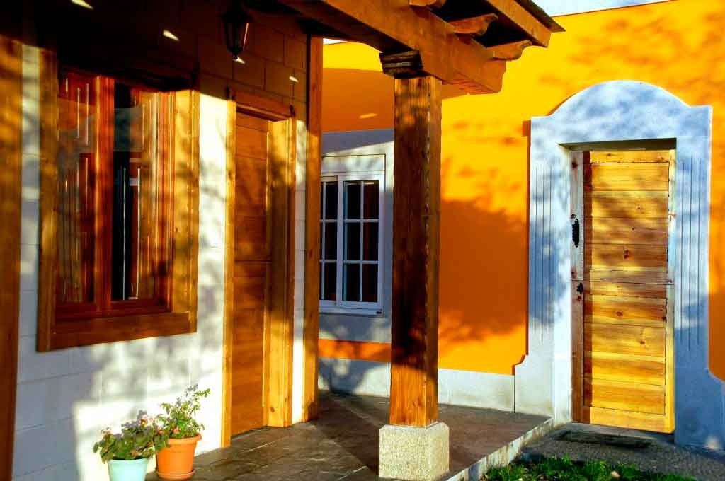 Una casa amarilla con un porche de madera y una puerta azul