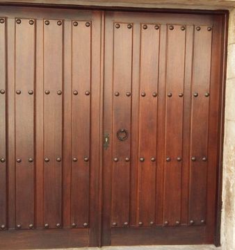 Una puerta de garaje de madera con una pared de ladrillos detrás.