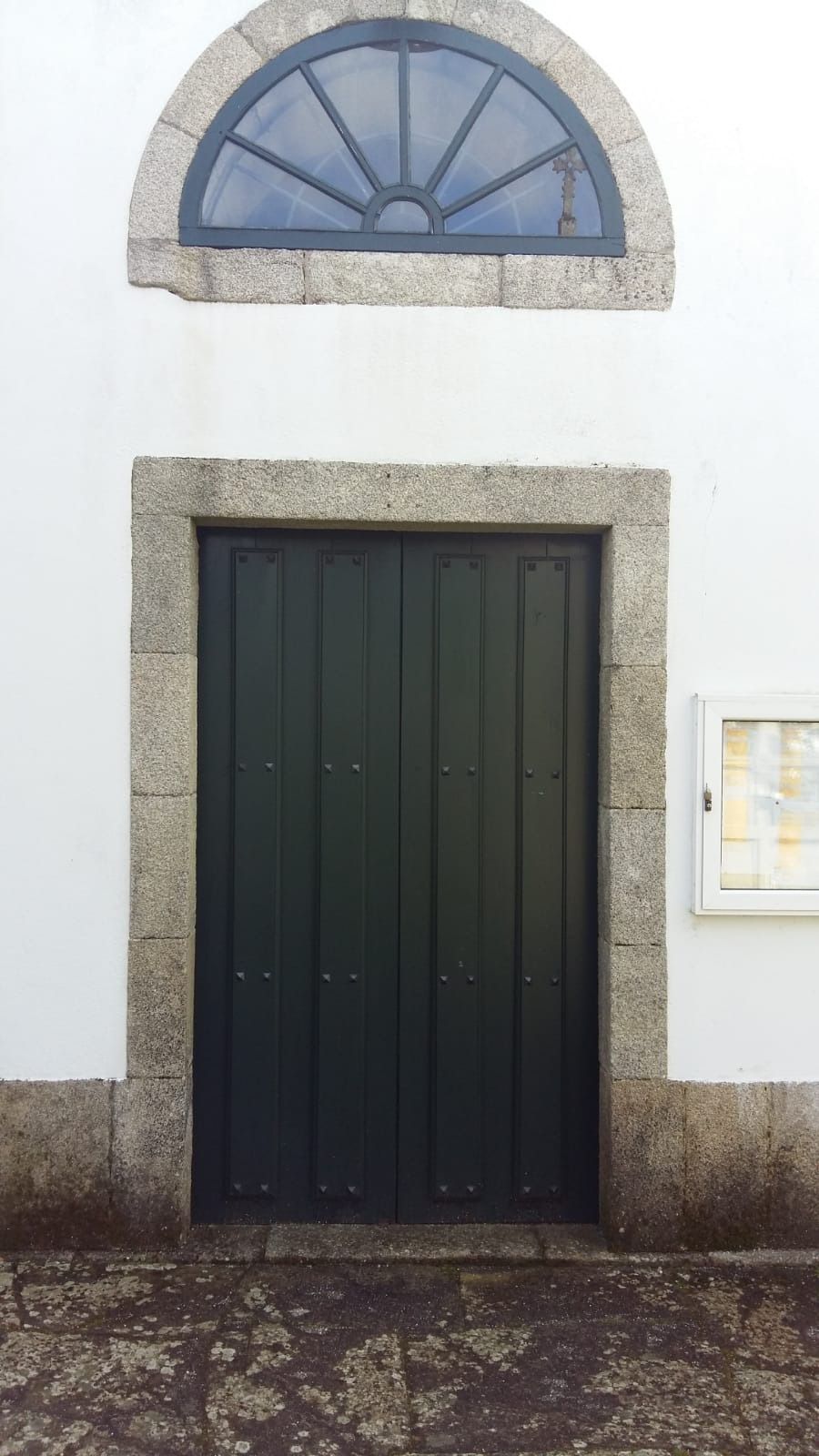 Una puerta negra con marco de piedra y una ventana en el costado de un edificio.