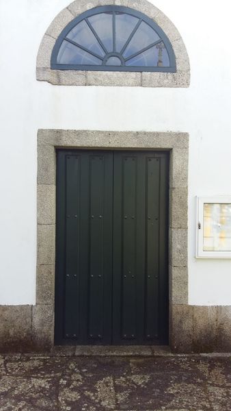 Una puerta negra con marco de piedra y una ventana en el costado de un edificio.