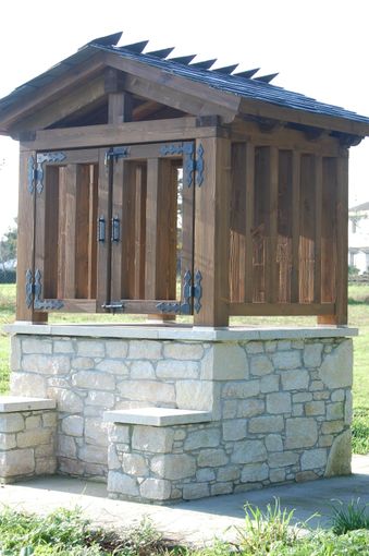 Un refugio de madera con base de piedra está situado en el césped.