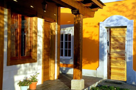 Una casa amarilla con un porche de madera y una puerta de madera