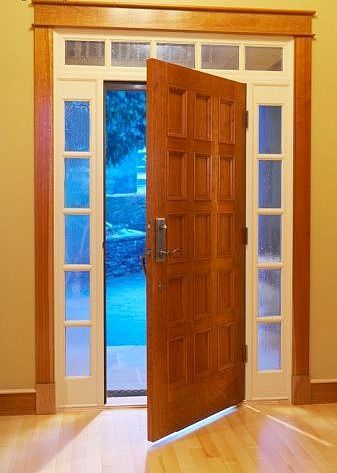 Una puerta de madera se abre a una habitación con una piscina al fondo.