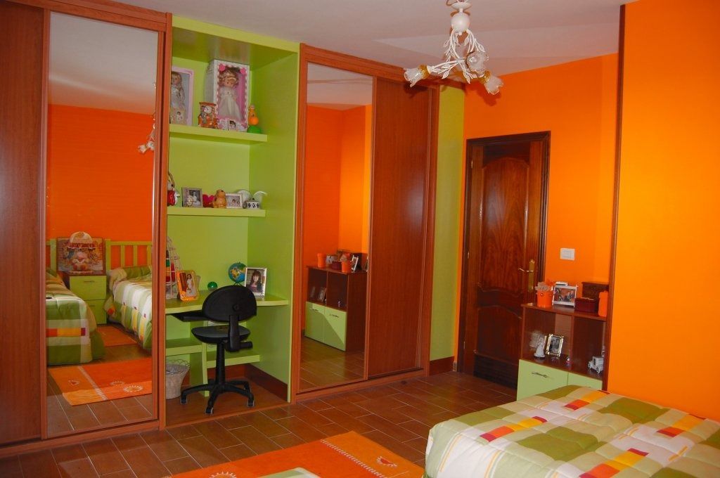 Un dormitorio con paredes naranjas y estantes verdes.