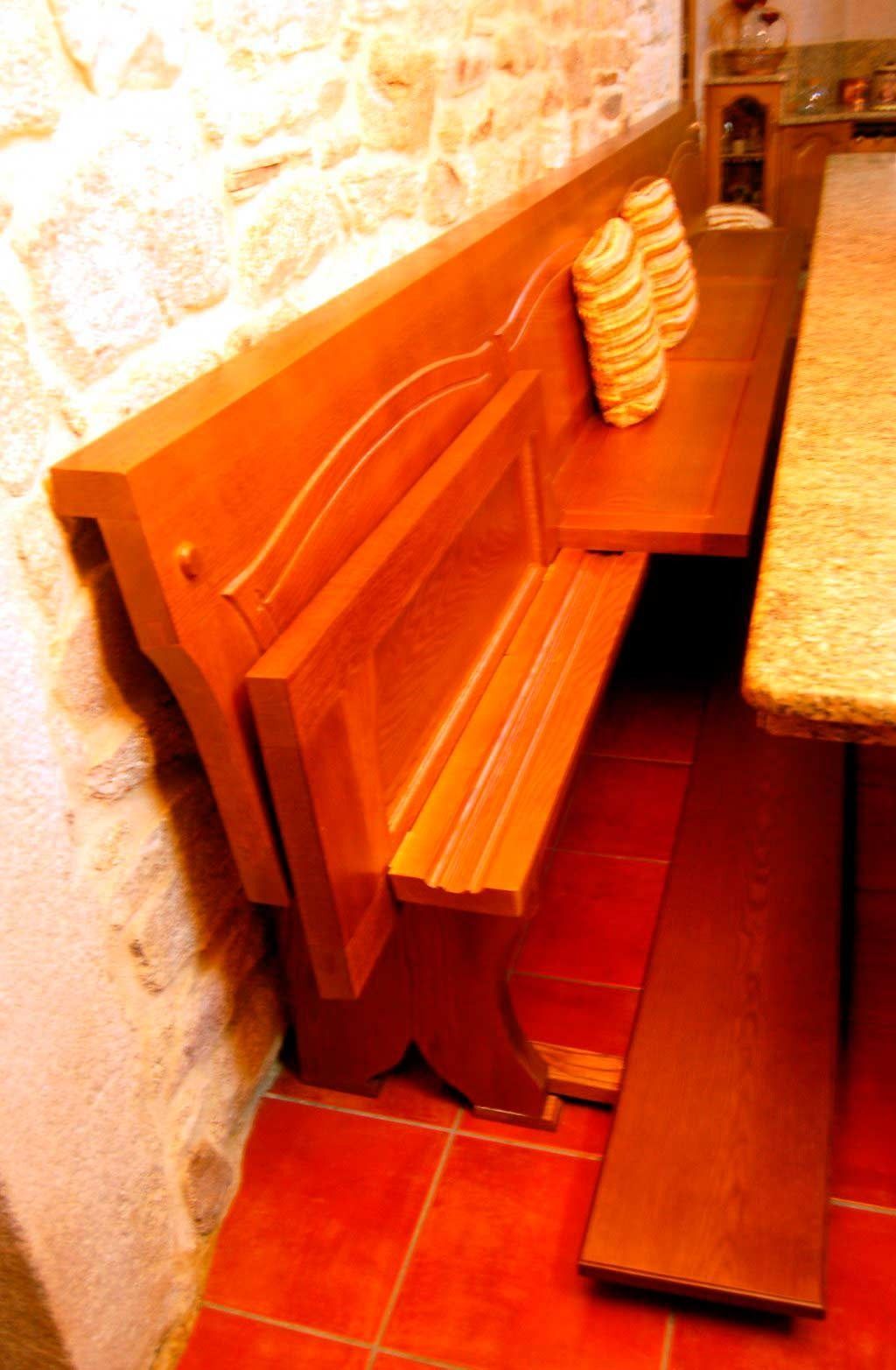 Un banco de madera se encuentra junto a una mesa en una habitación.