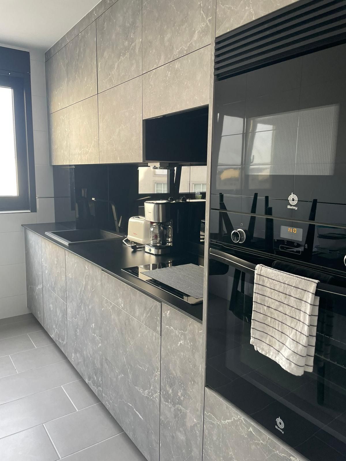 Una cocina con gabinetes negros y un horno negro.