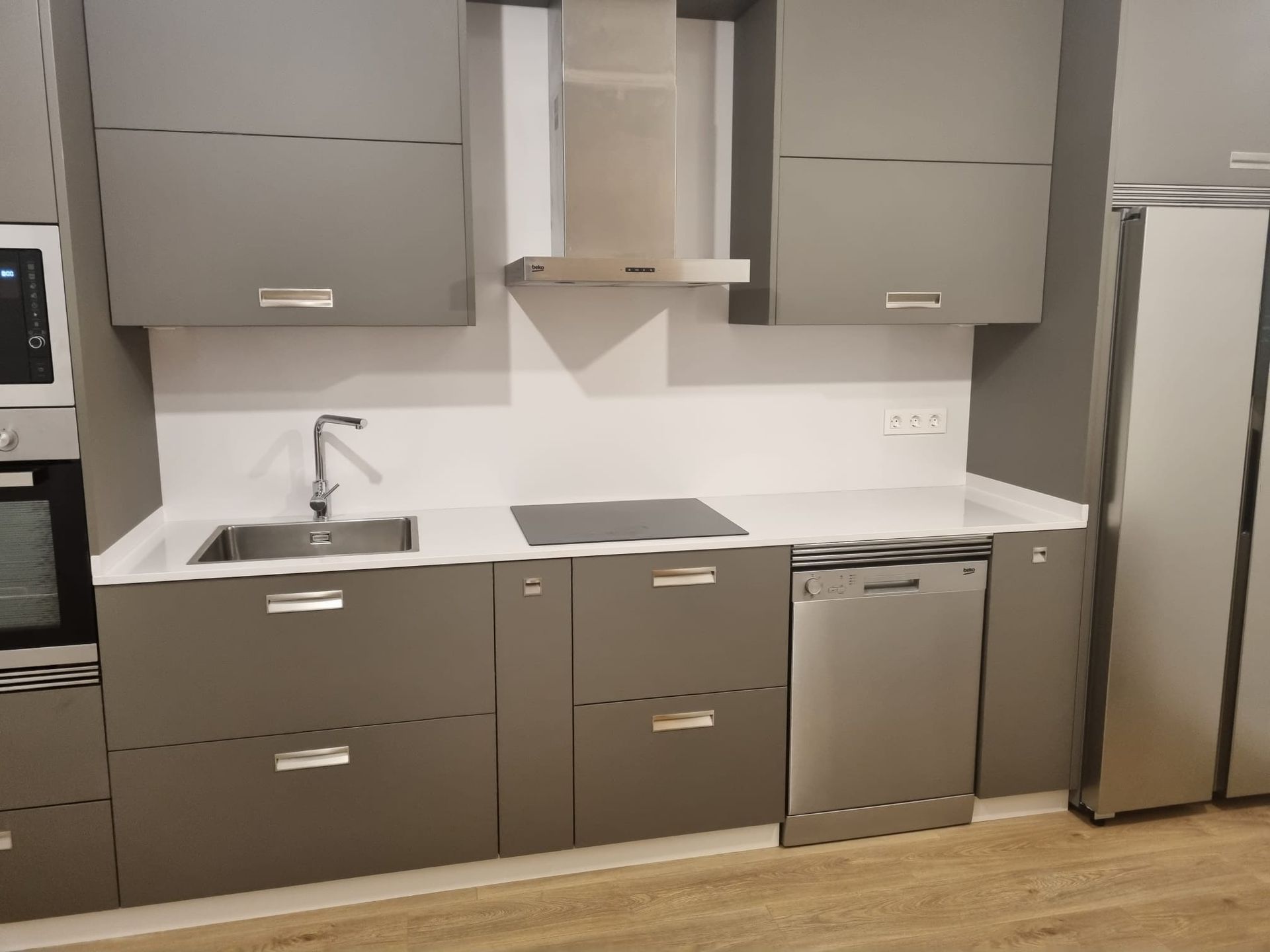 Una cocina con gabinetes grises y lavavajillas de acero inoxidable.