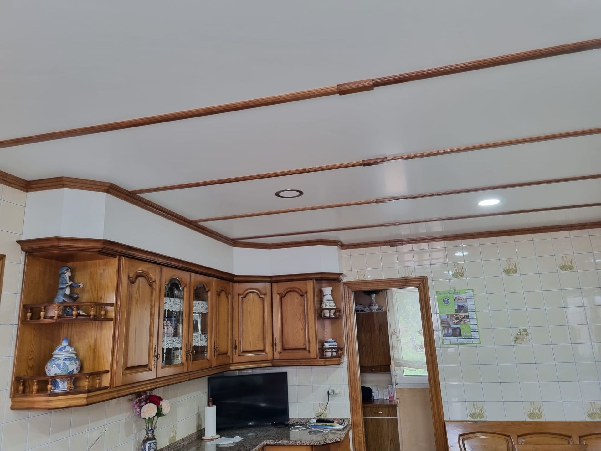 Una cocina con gabinetes de madera y un techo blanco.