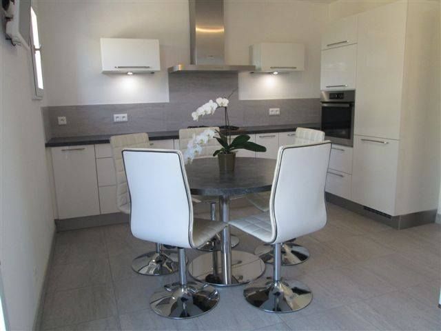 Cuisine claire avec table à manger ronde et quatre sièges blancs