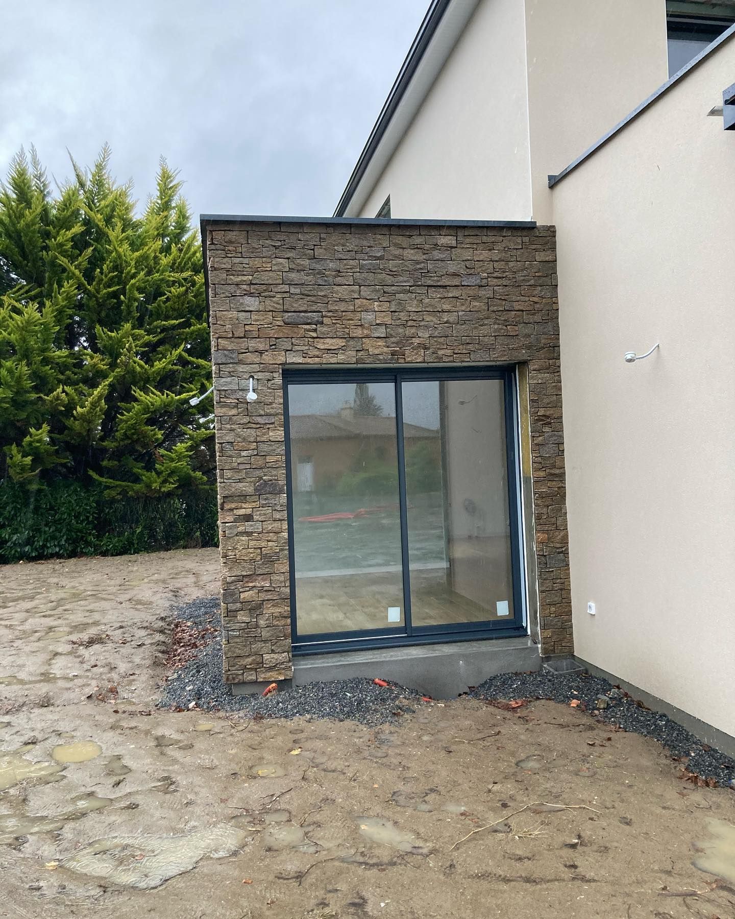 Extension de maison avec mur recouvert de briquette et une porte-fenêtre