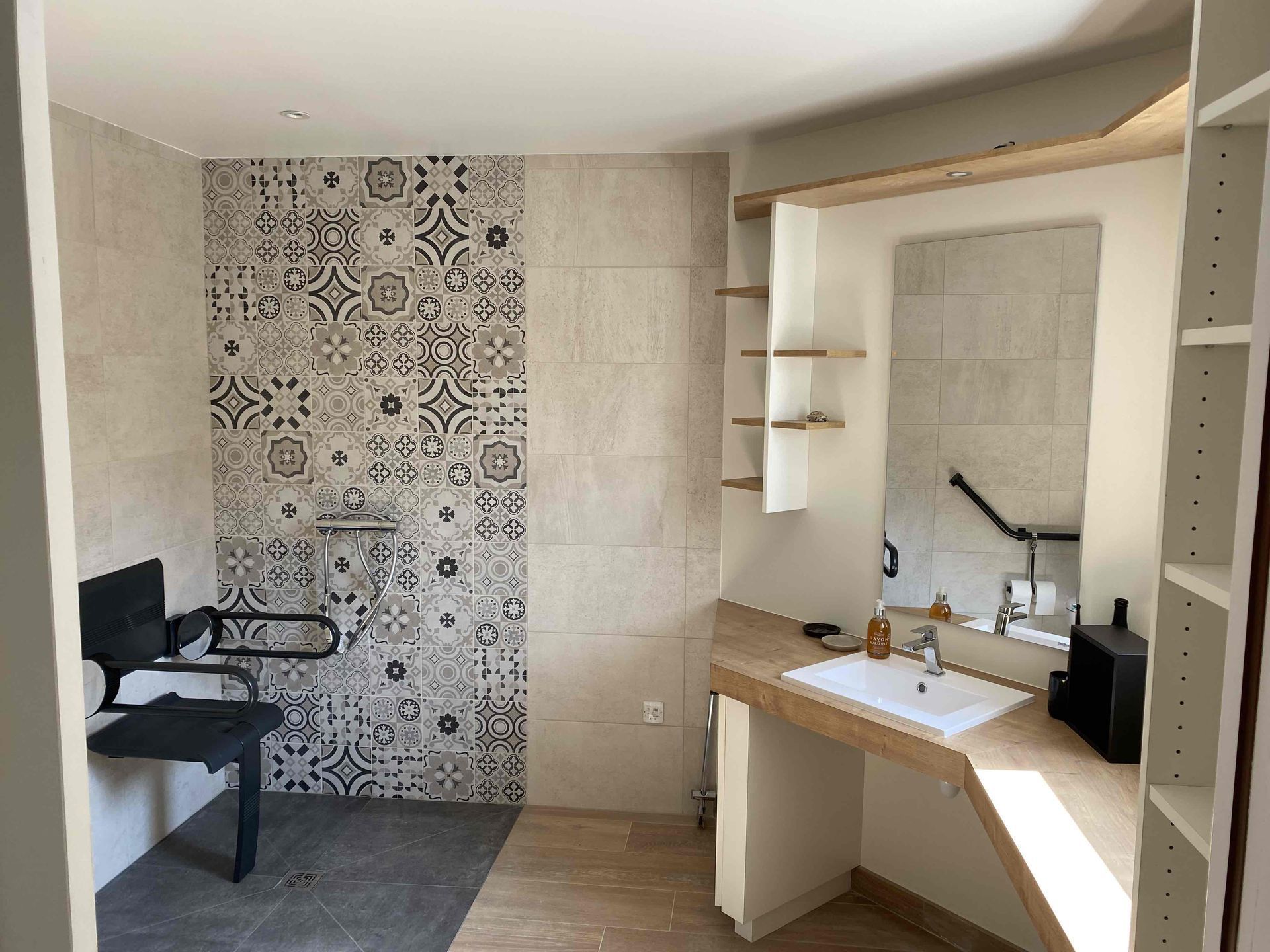 Salle de bains pour personnes à mobilité réduite avec carrelage à motif au niveau de la douche