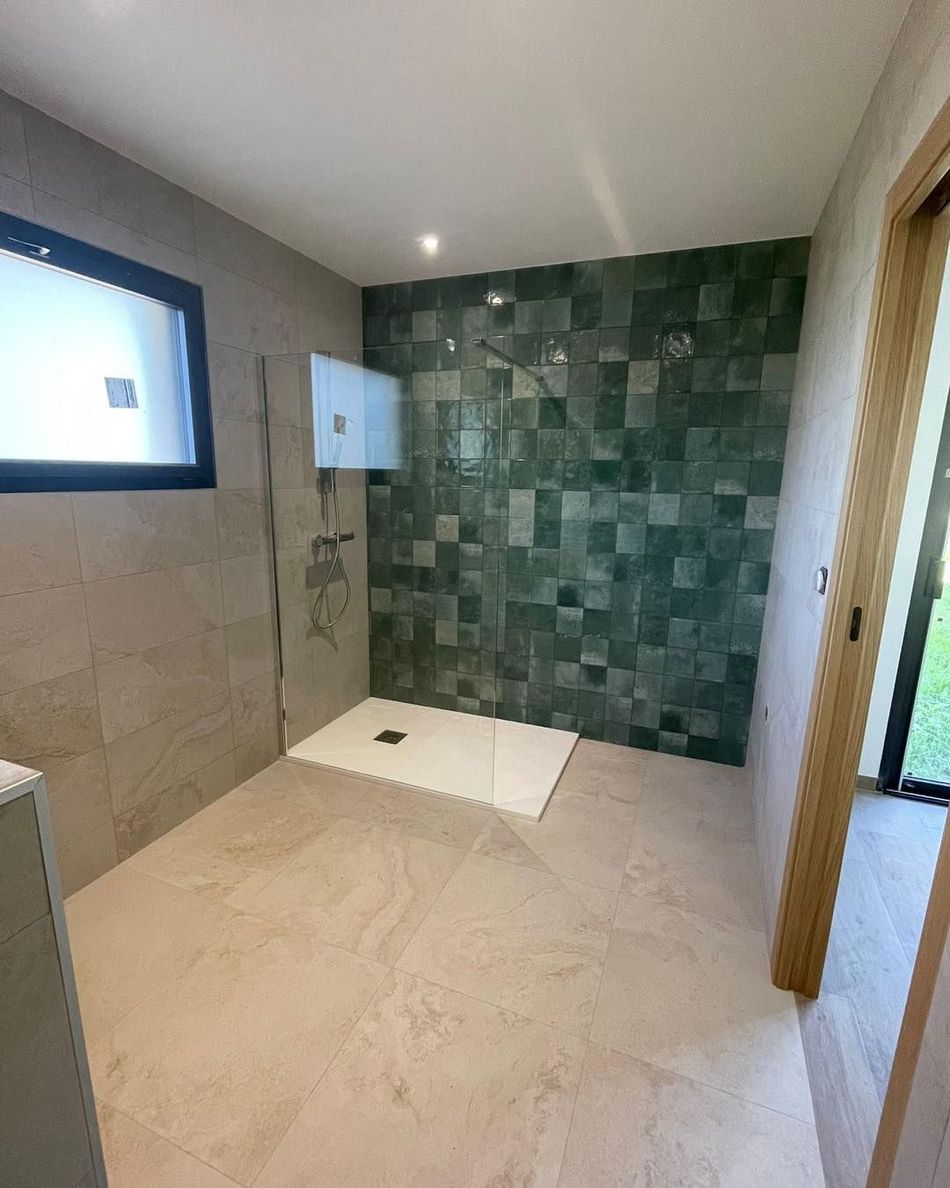 Salle de bain moderne avec douche carrelée de beige, mur d'accent en mosaïque verte et éclairage par fenêtre