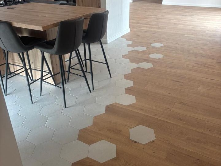 Pièce moderne avec carrelage hexagonal blanc et bois au sol, à côté d'une table et de chaises noires