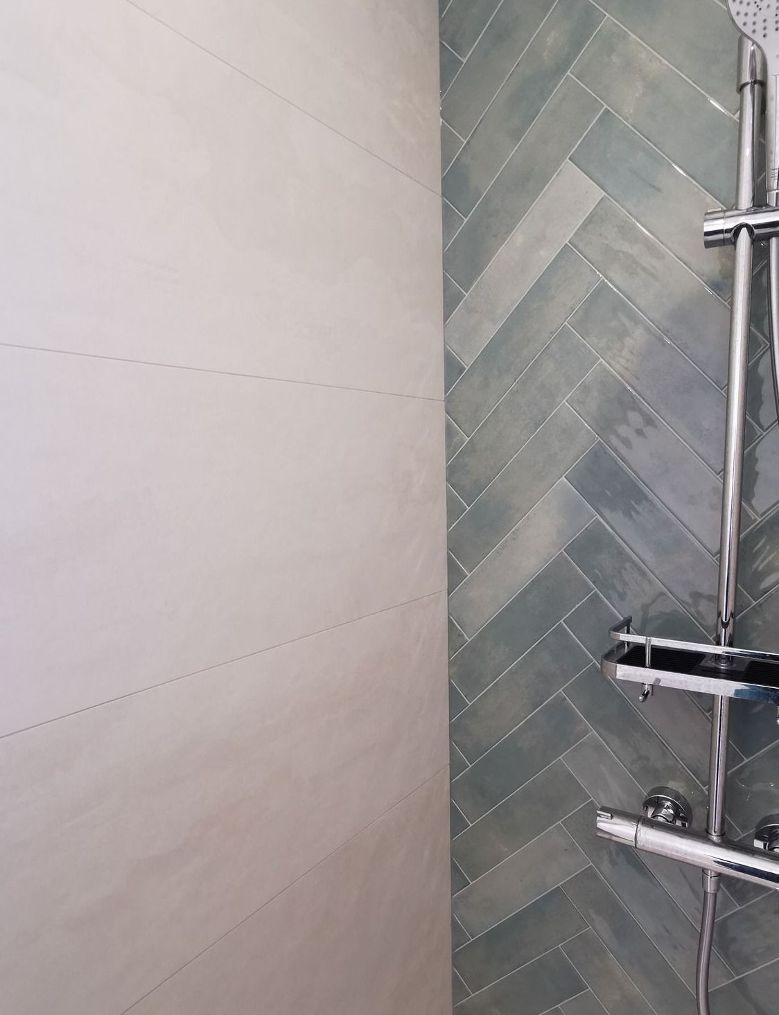 Mur de douche de salle de bain avec carrelage beige, carrelage gris à chevrons et robinetterie chromée