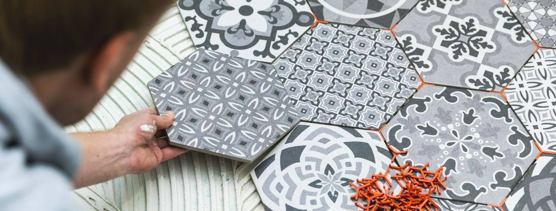 Main d’un carreleur qui pose un carrelage hexagonal