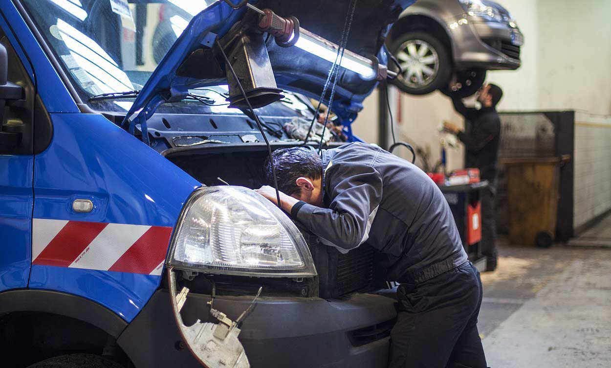mécanicien la tête dans le moteur d'une camionnette bleue
