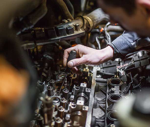 vue de près d'une main de mécanicien avec un tournevis dans un moteur de voiture