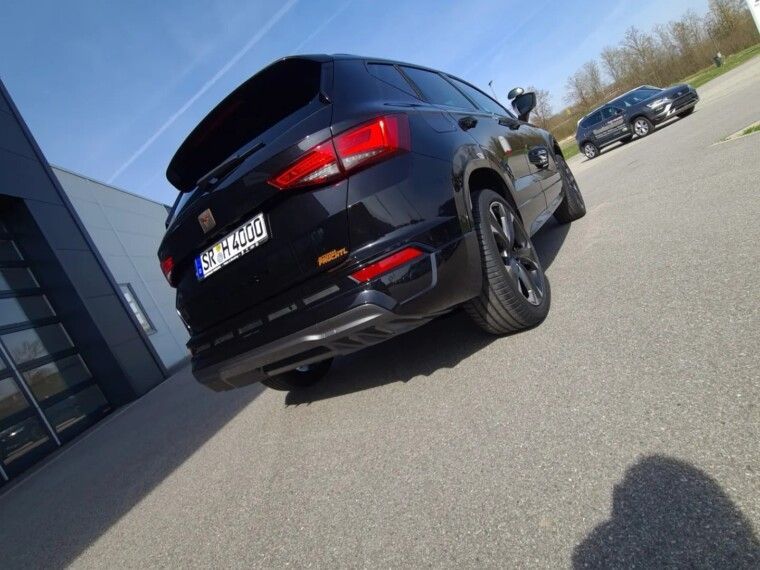 A black SEAT SUV parked outdoors on an asphalt lot, viewed from a low-angle rear perspective under a clear blue sky.
