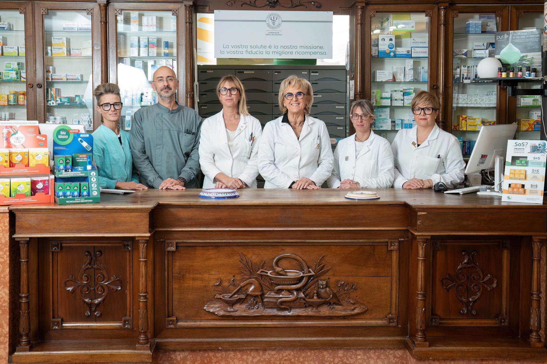 staff della farmacia dietro al bancone di legno intarsiato