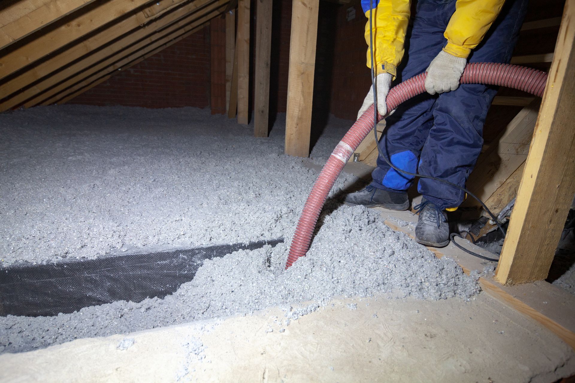 Employé qui souffle de la ouate de cellulose dans des combles