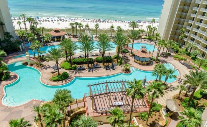 Shores of Panama resort pool framed by palm trees with Gulf of Mexico beach view, Panama City Beach