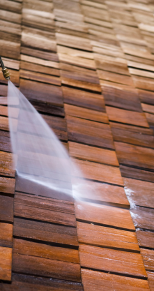 Nettoyage d'un toit en bois au nettoyeur haute pression, montrant une différence de couleur visible.