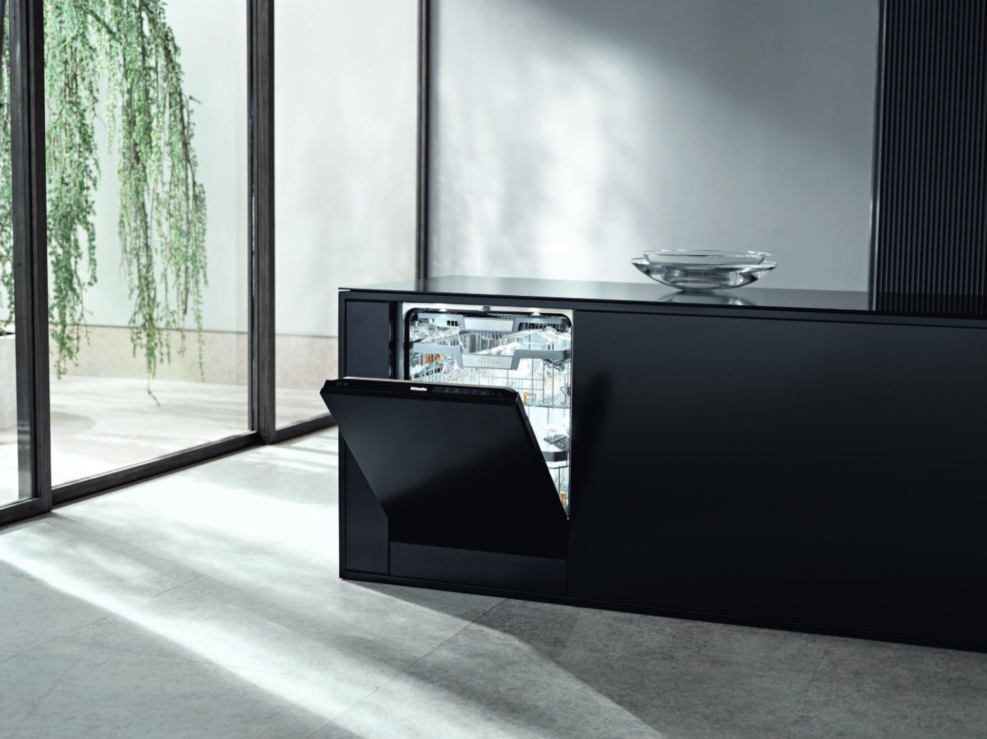 Schwarzer Geschirrspüler mit offener Tür, eingebaut in eine schwarze Arbeitsplatte, in einer modernen Küche.