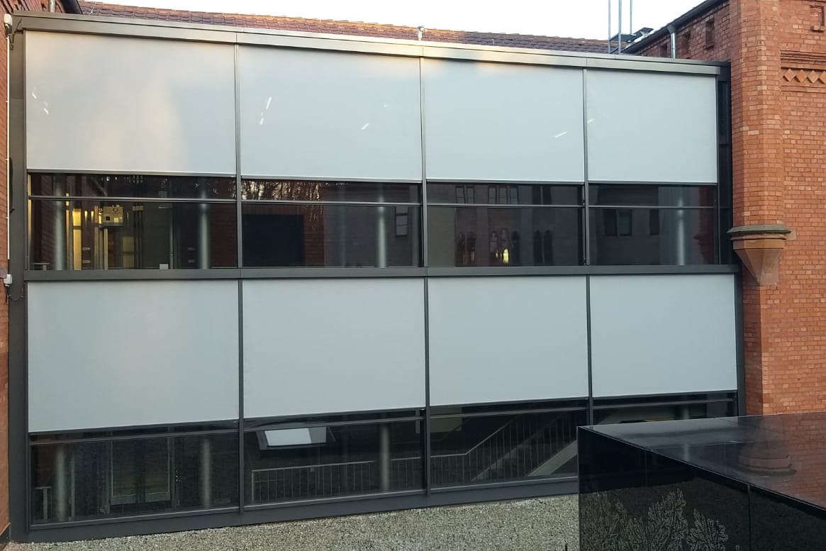 Ein Gebäude mit vielen Fenstern und einem Teich davor.