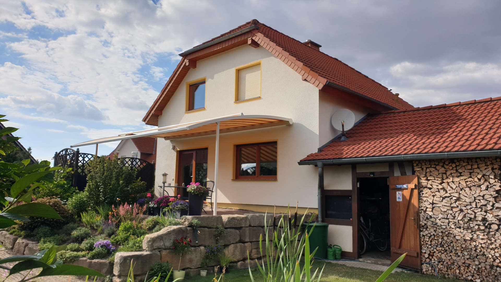 Ein Haus mit einem roten Ziegeldach und einer Steinmauer davor.