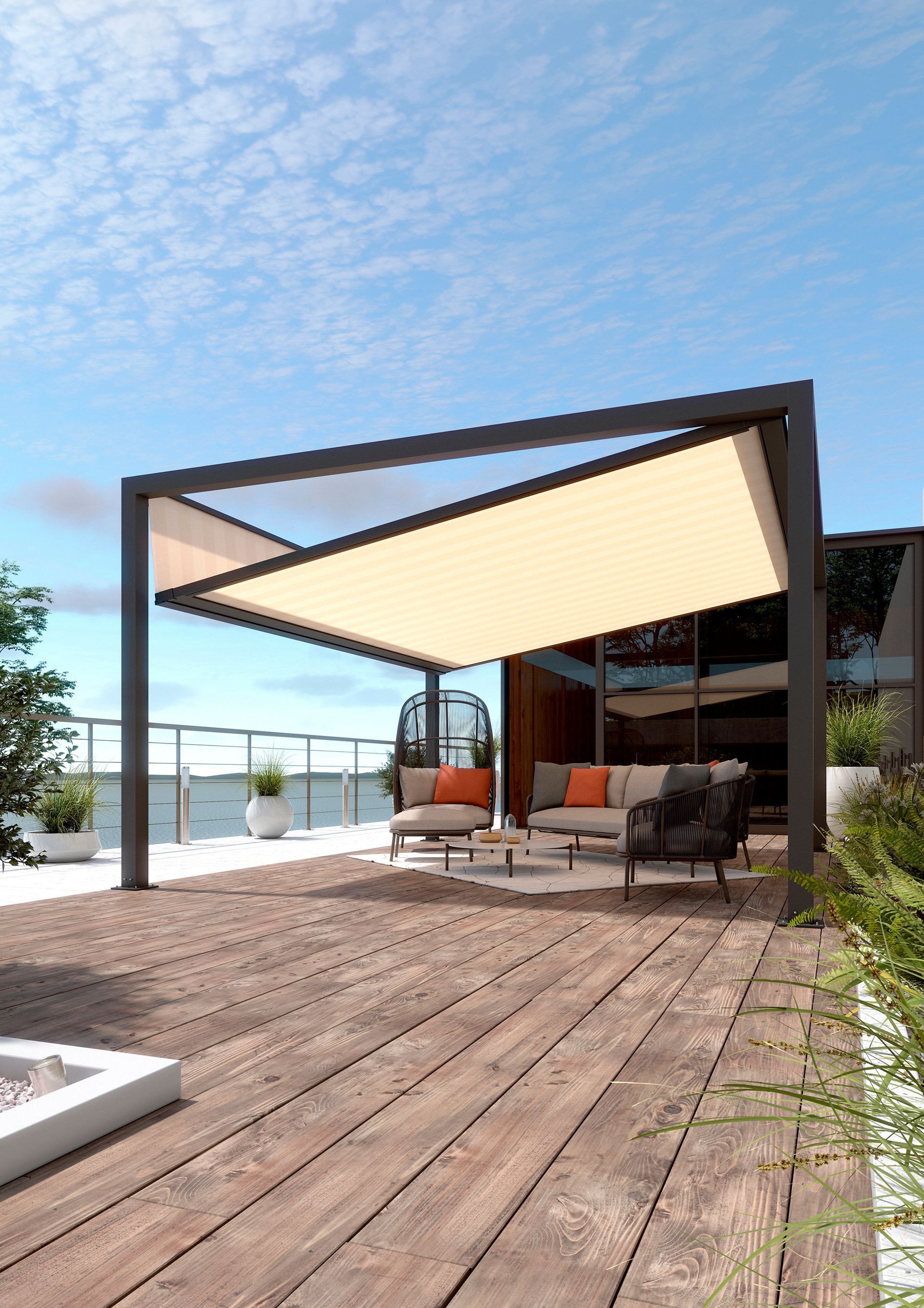 Eine moderne Terrasse mit einziehbarem, cremefarbenem Vordach, Gartenmöbeln und einer Holzterrasse mit Blick auf die Küste.