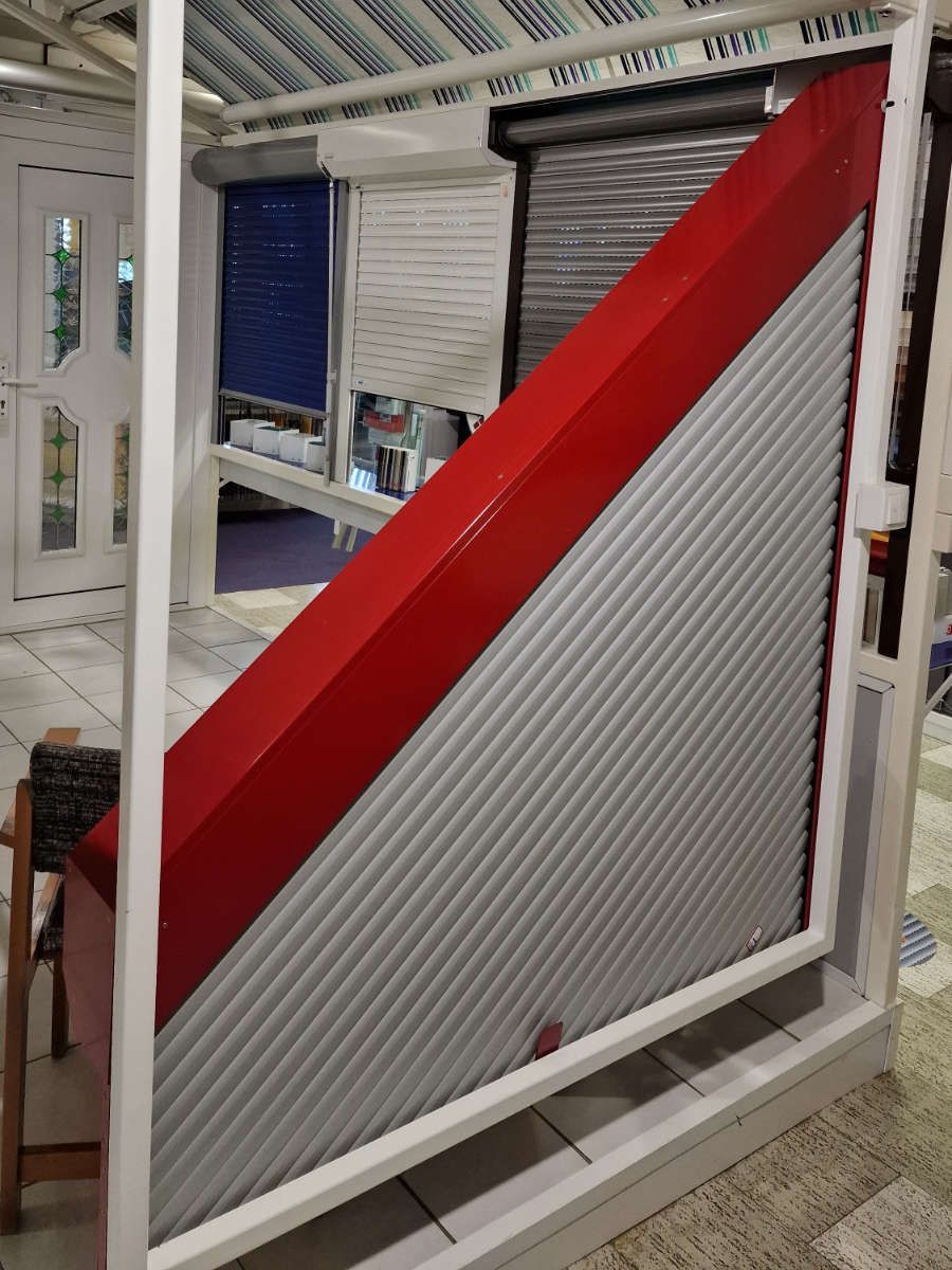 In einem Geschäft ist ein rot-weißer Rollladen ausgestellt.