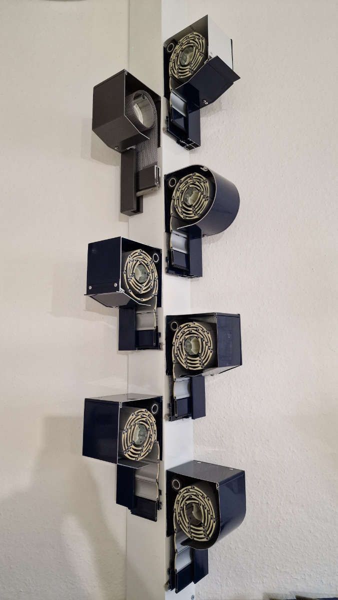 Eine Reihe schwarzer Kästen, die an einer weißen Wand hängen.