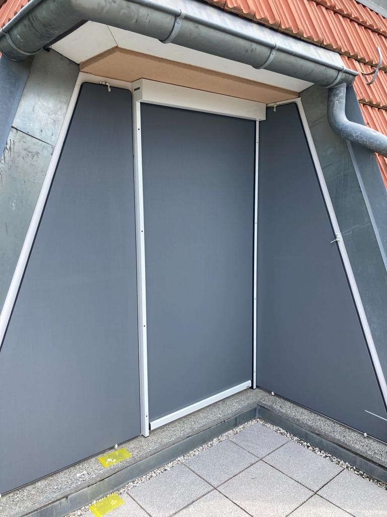 An der Seite eines Gebäudes befindet sich ein Fenster mit Jalousie.