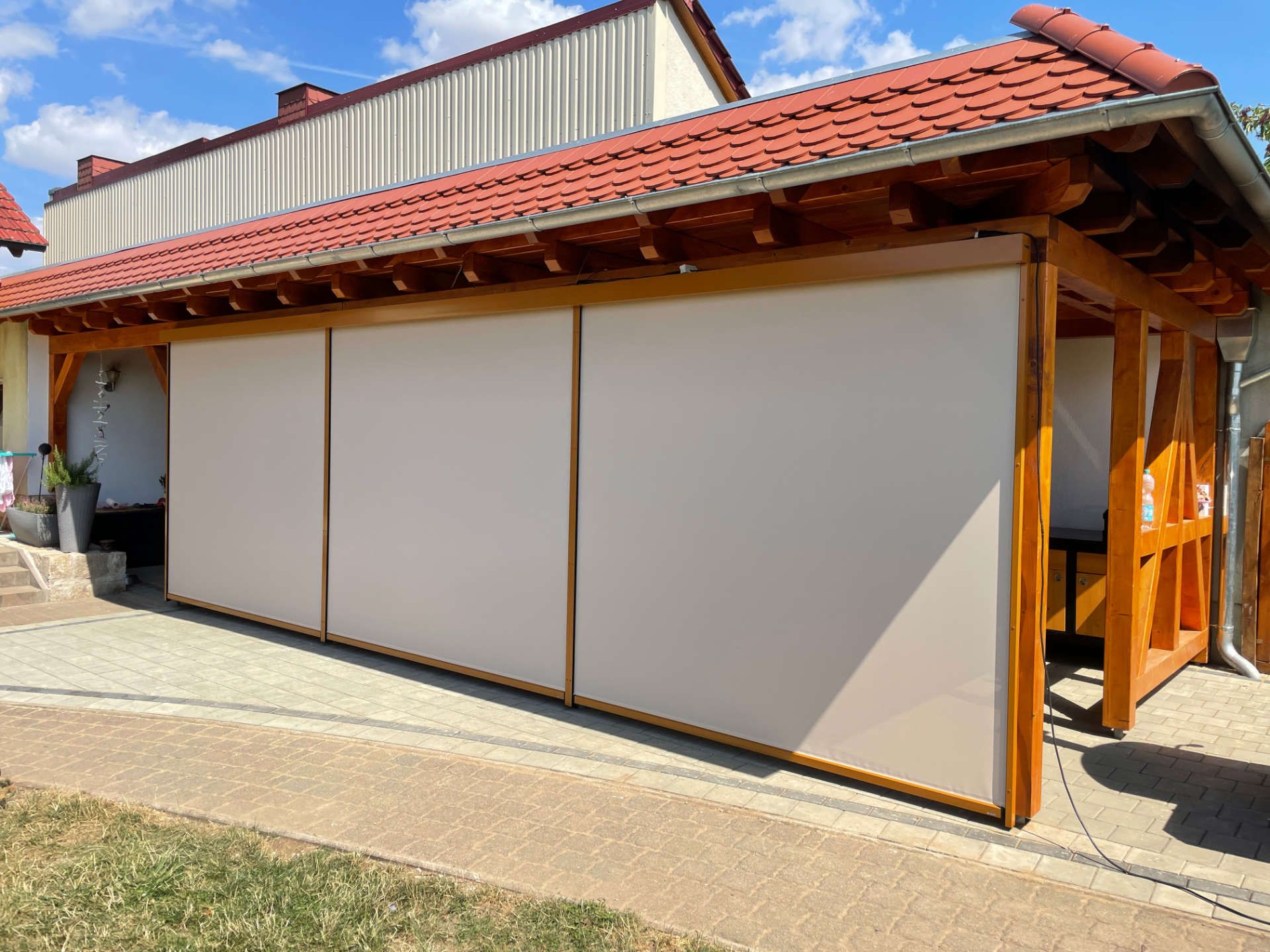 Ein Haus mit einem roten Dach Sonnenschutz an einem Carport.