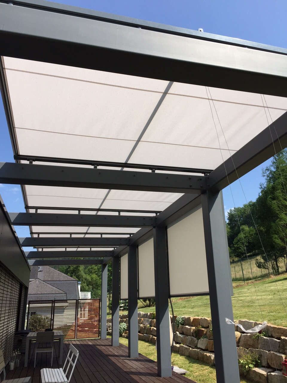 Eine Pergola mit weißem Dach und weißen Jalousien.