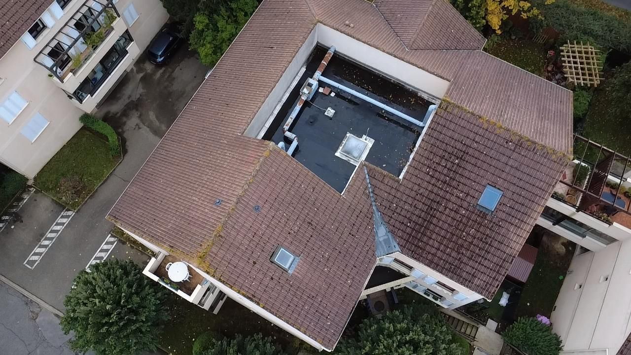 Vue aérienne d'un immeuble à plusieurs étages avec un toit de tuiles.