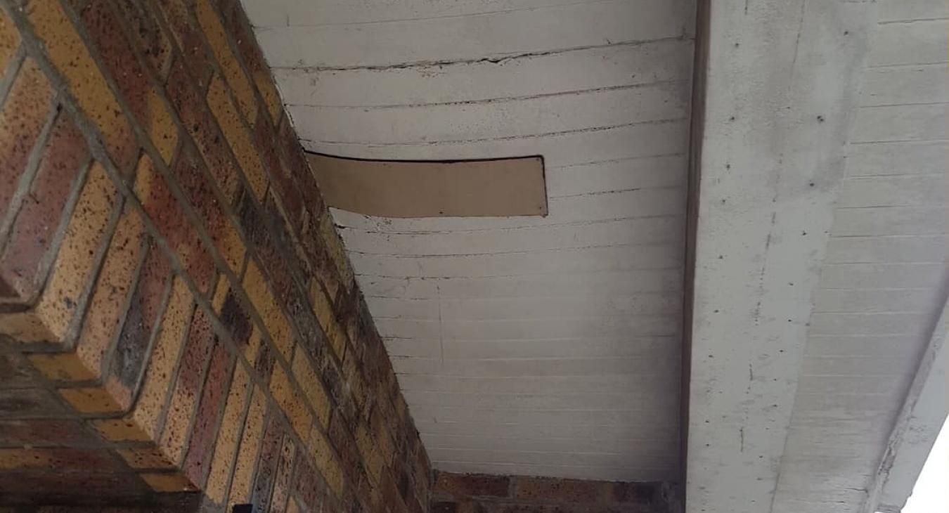 Mur de briques percé d'une ouverture donnant sur un plafond en béton.