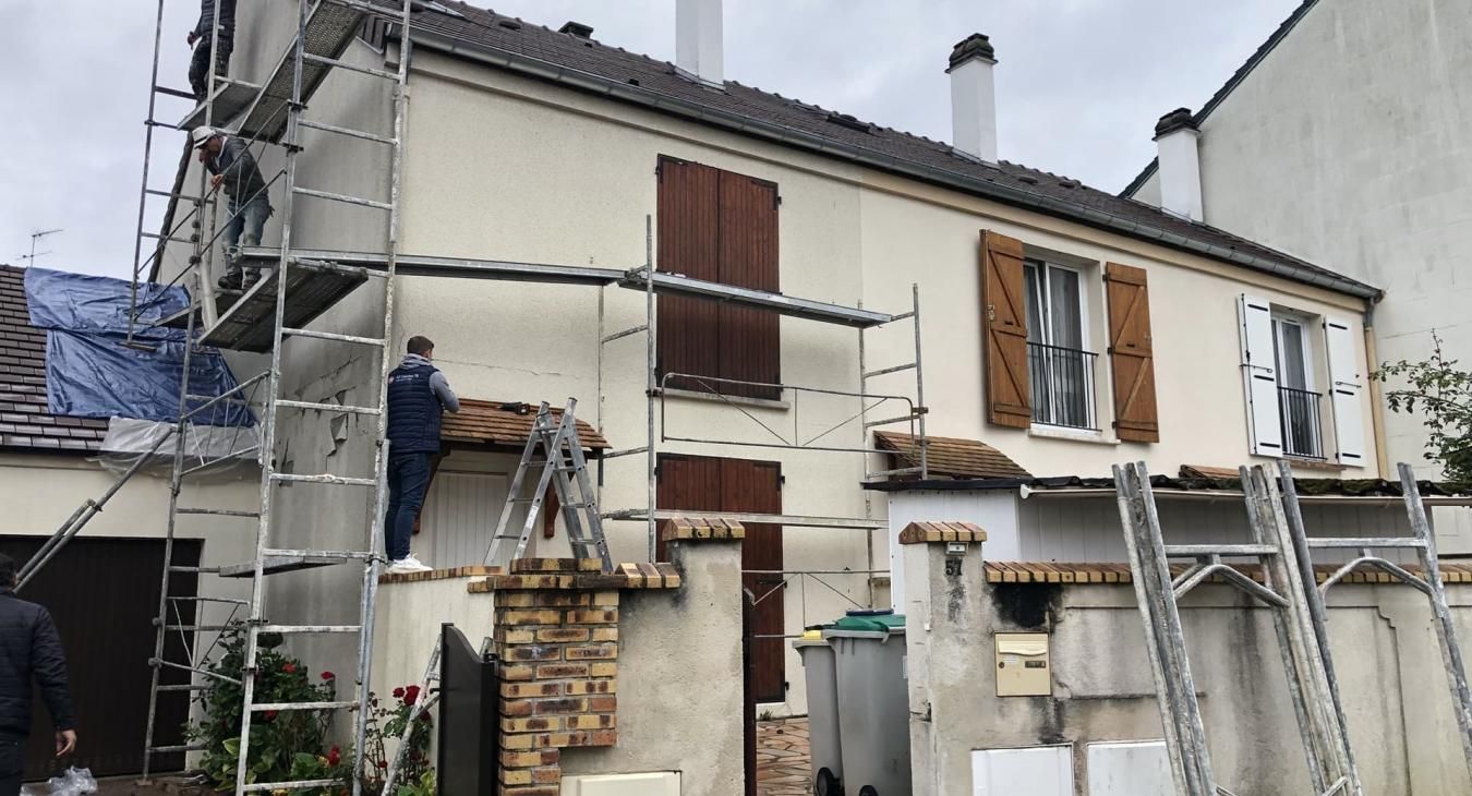 Des ouvriers sur des échafaudages réparent l'extérieur d'une maison à deux étages avec des volets.