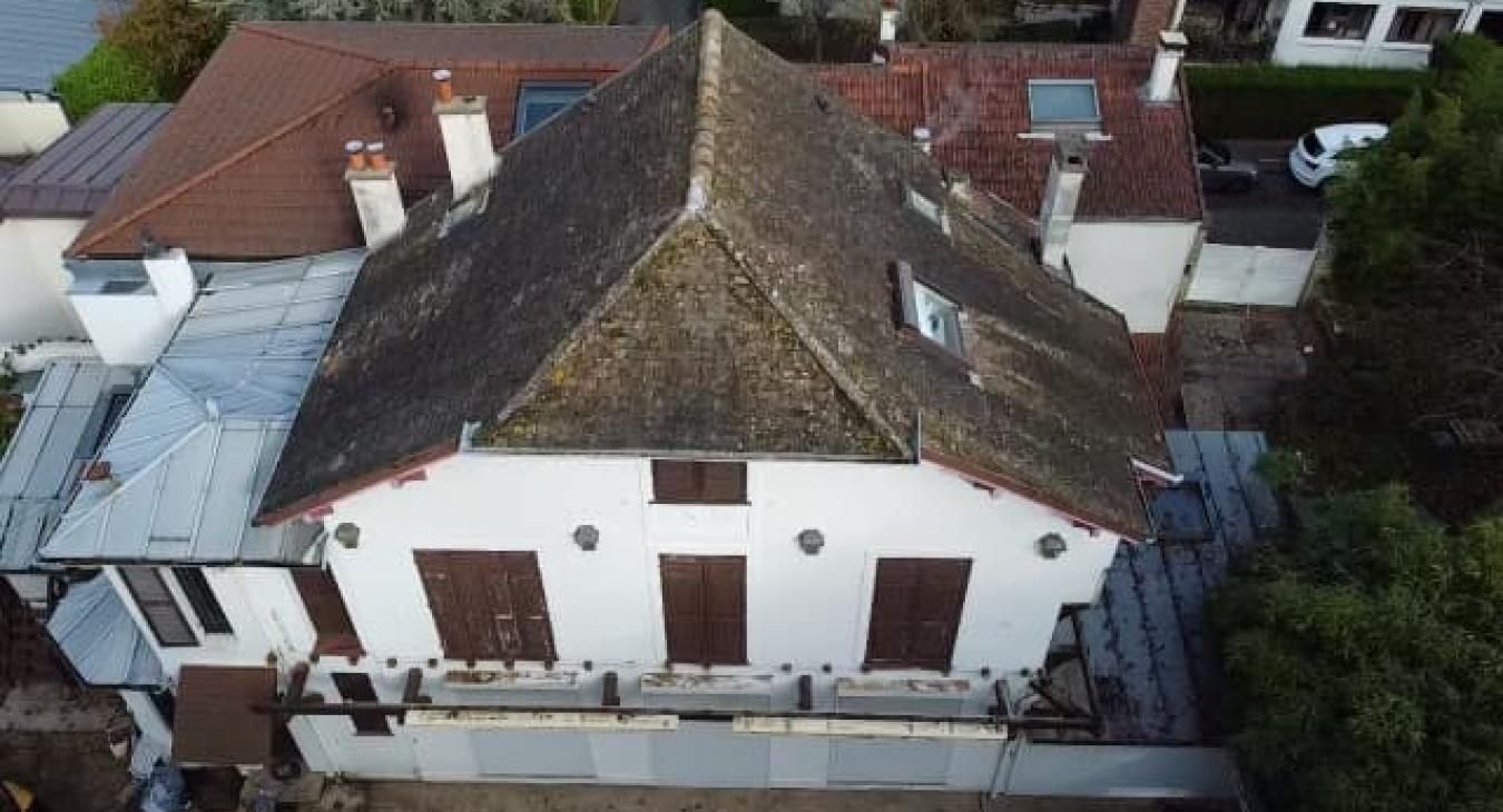 Vue aérienne d'un bâtiment blanc avec un toit marron et des volets marron.