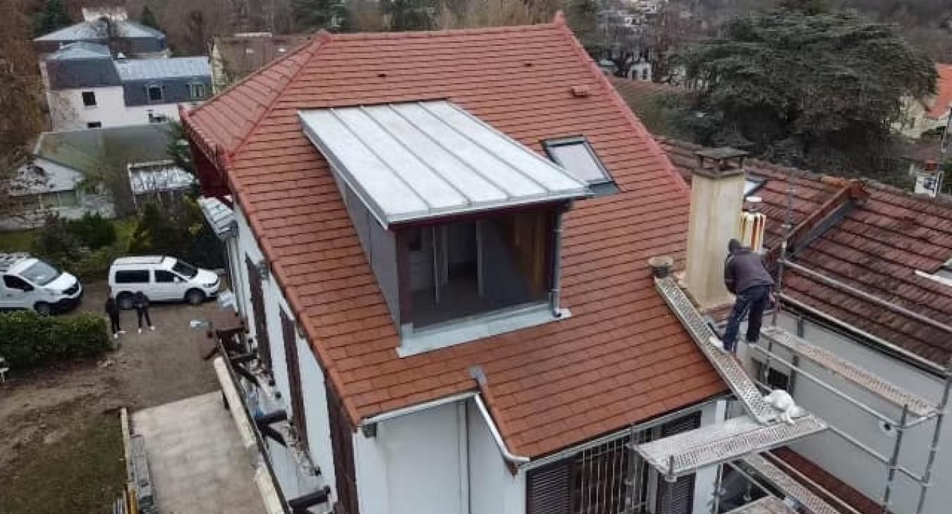 Maison au toit rouge, ouvriers sur échafaudage, réparation de cheminée.