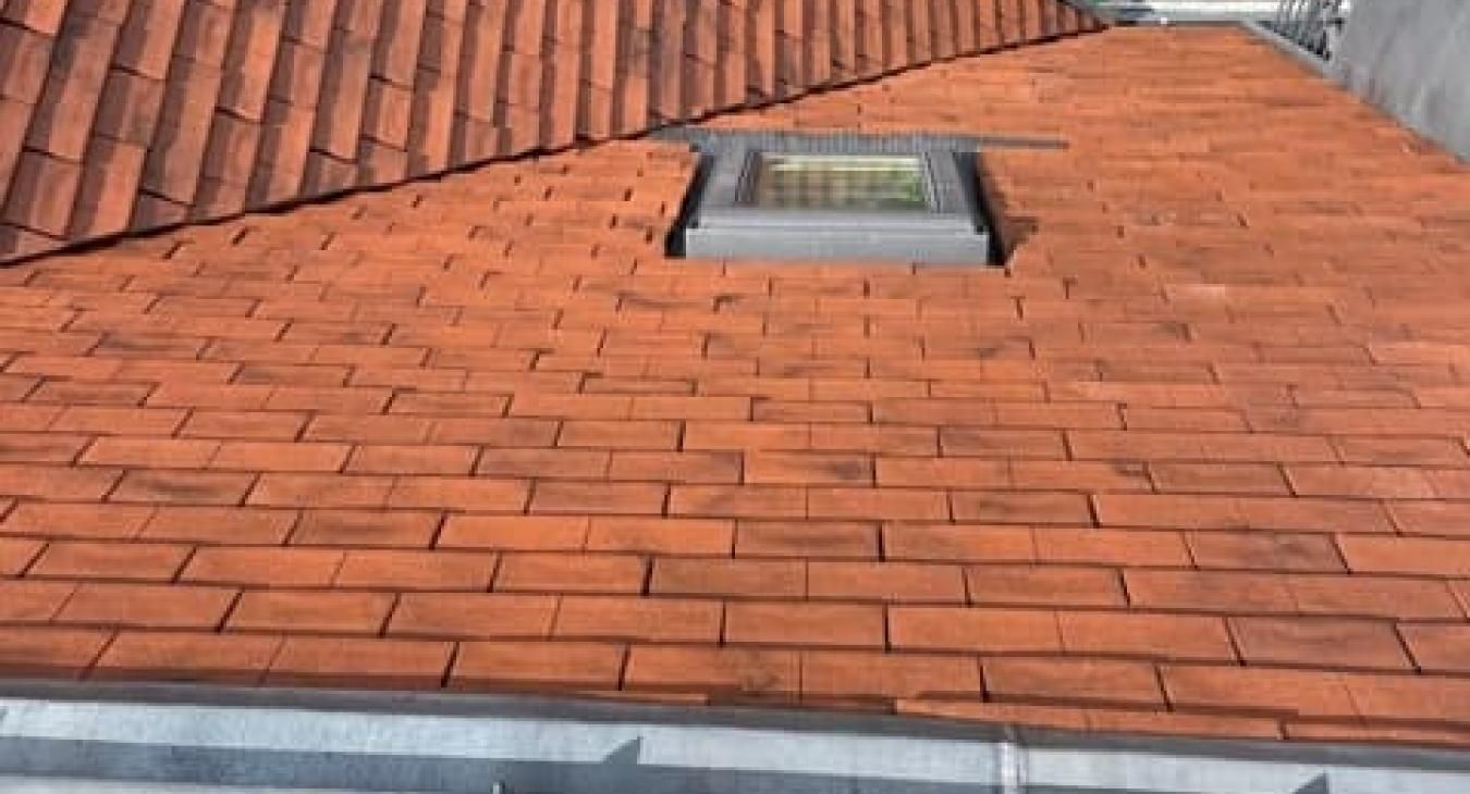 Toit en tuiles rouges avec une lucarne rectangulaire.