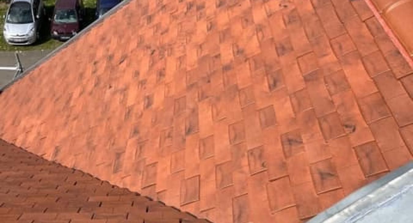 Toiture en tuiles rouges, laissant apparaître la texture et le motif des tuiles.