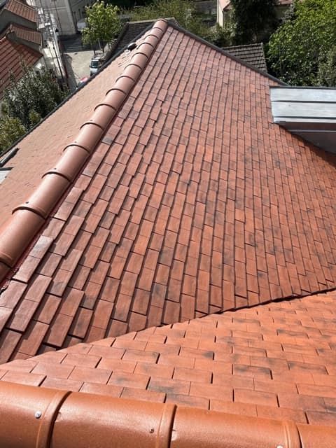 Toiture en tuiles rouges avec faîtières incurvées, vue de dessus, dans un cadre résidentiel.