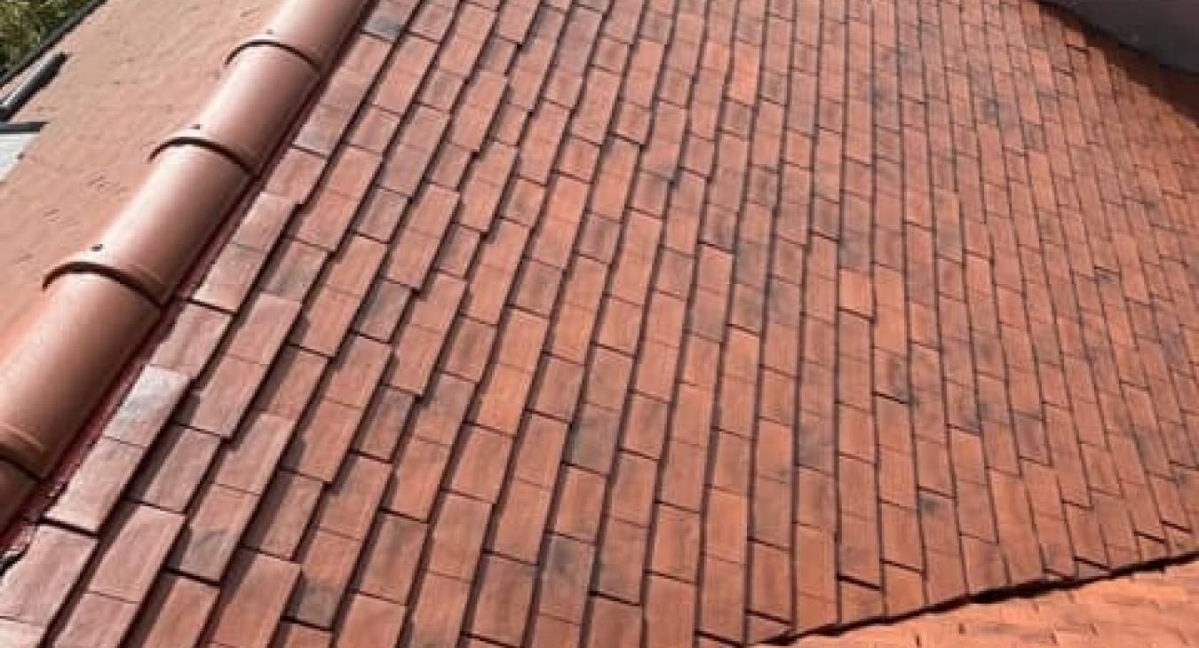 Toiture en tuiles de terre cuite rouge à bords arrondis.