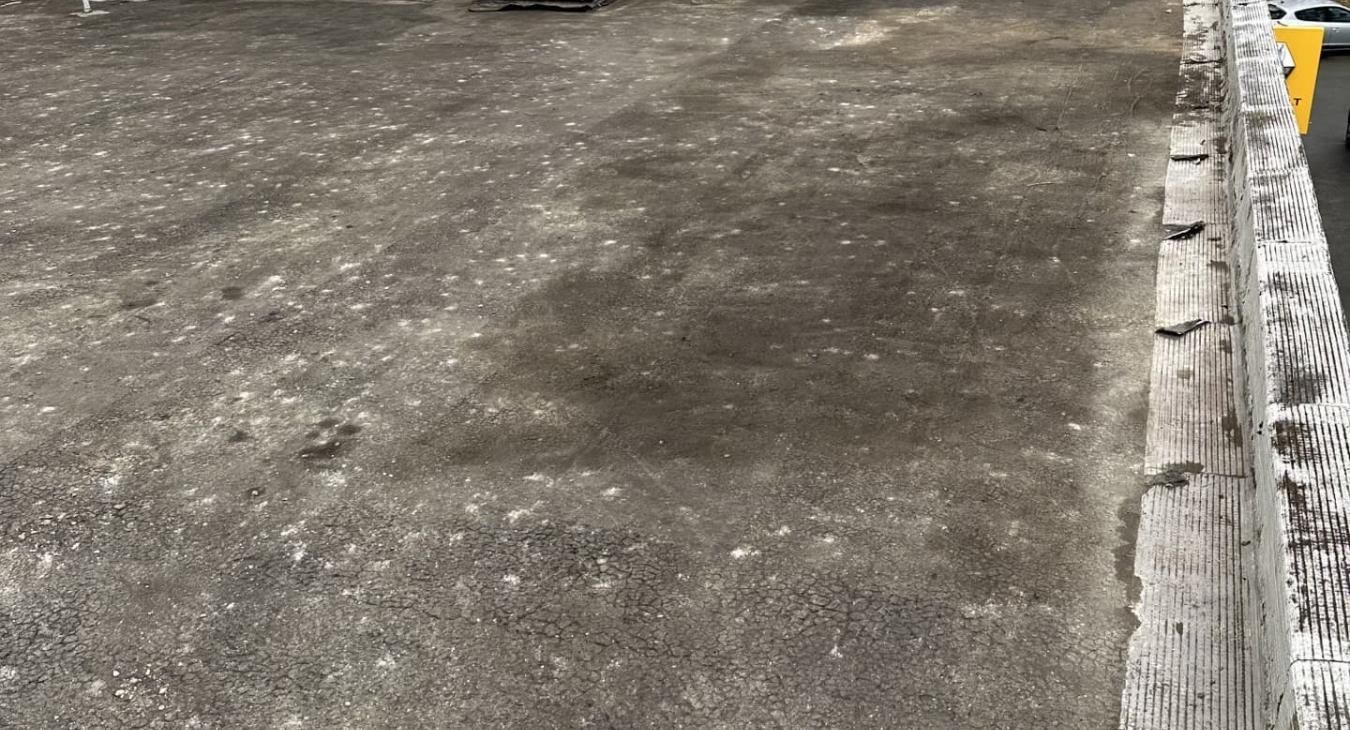 Surface en béton foncé texturé avec un bord en bois.